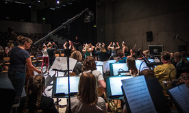 An orchestra and group of dancers rehearsing.