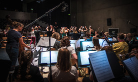An orchestra and group of dancers rehearsing.
