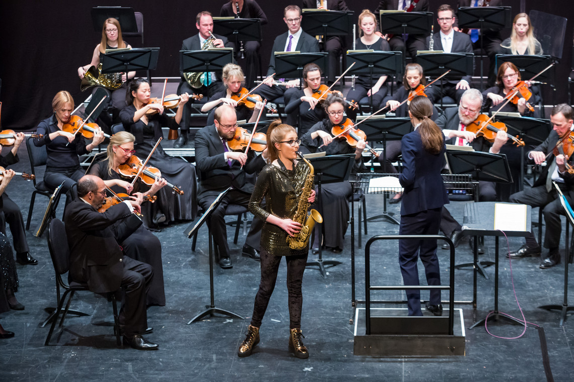 A saxophonist performing with an orchestra.