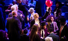 A woman in a group of people reaching for a red balloon.
