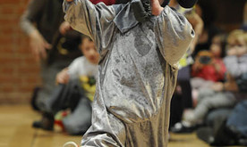 A young child dressed in an elephant costume holding hands with an adult out of shot