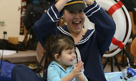 A young girl clapping, sat in front of the presenter in a large inflatable boat.