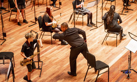 A young white boy and a black man on stage reaching out for an elbow bump