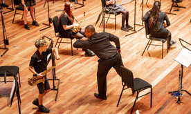A young white boy and a black man on stage reaching out for an elbow bump