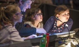 Three girls sit with a man at a sound desk.